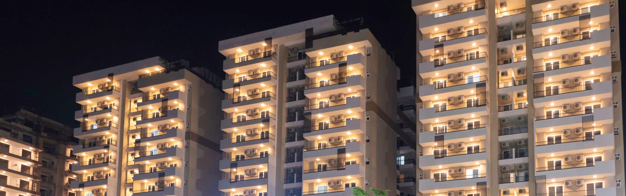 Lit residences at dusk in a Tricity development