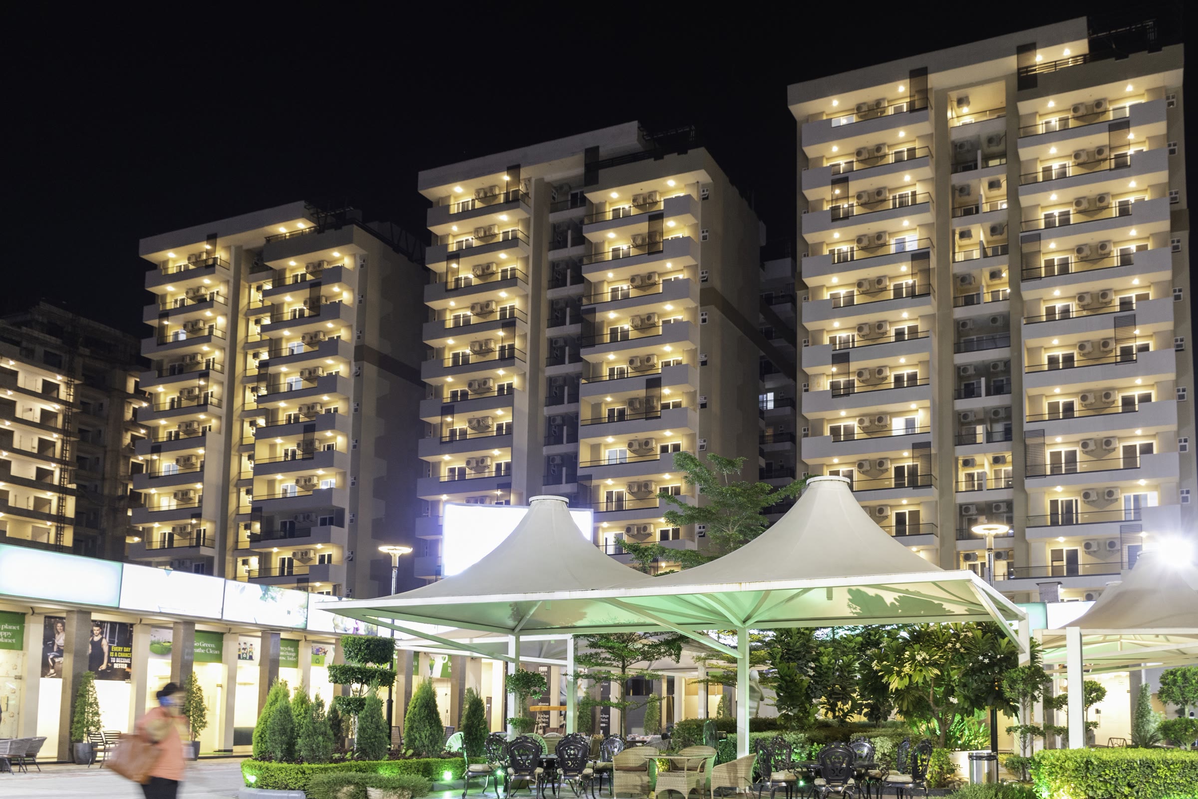 Landscaped courtyard lit at night beneath residential towers in Zirakpur