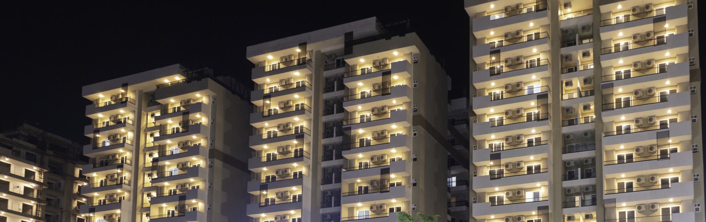 Lit residences at dusk in a Tricity development